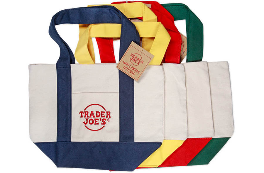 Set of reusable canvas tote bags in assorted colors with 'Trader Joe's' logo and colorful handles (blue, yellow, red, green).