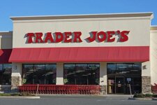 Exterior of a Trader Joe's store with a red awning and shopping carts outside the entrance. This is the storefront signage and facade of a grocery store.