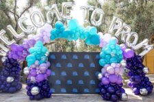 Balloon arch spelling 'Welcome to Prom' over a blue backdrop for a high school prom event.
