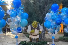 Balloon Celebrations - Shrek | Santa Monica Sun Life-sized Shrek statue standing among blue, silver, and clear balloons at an outdoor festival.