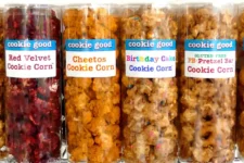 Row of four clear snack bags labeled 'cookie good' with flavors: Red Velvet Cookie Corn, Cheetos Cookie Corn, Birthday Cake Cookie Corn, and Gluten-Free PB Pretzel Bar Cookie Corn.