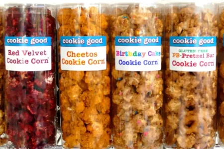 Row of four clear snack bags labeled 'cookie good' with flavors: Red Velvet Cookie Corn, Cheetos Cookie Corn, Birthday Cake Cookie Corn, and Gluten-Free PB Pretzel Bar Cookie Corn.