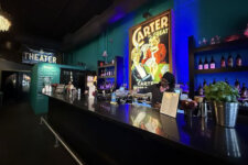 Illusion Magic Lounge bar | Santa Monica Sun Bar counter inside a theater lobby with a bartender serving drinks and a large vintage Carter poster behind him.