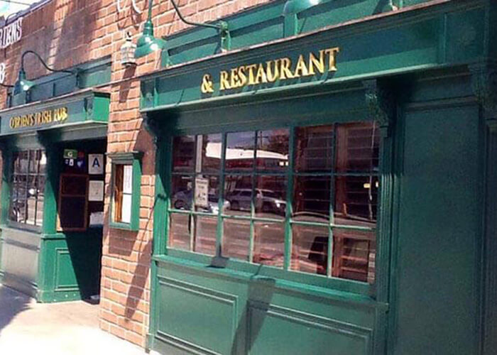 Green storefront with large windows and gold sign reading '& RESTAURANT' on a brick building exterior.