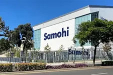 Exterior of a modern high school building with a large 'Samohi' sign, fenced grounds and trees.