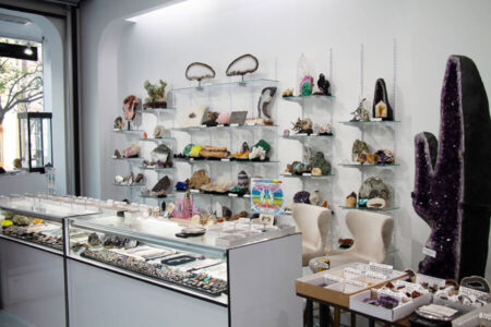 Glass display cases and shelves filled with colorful minerals, geodes, and amethyst crystals at Wonders of the World in Santa Monica.