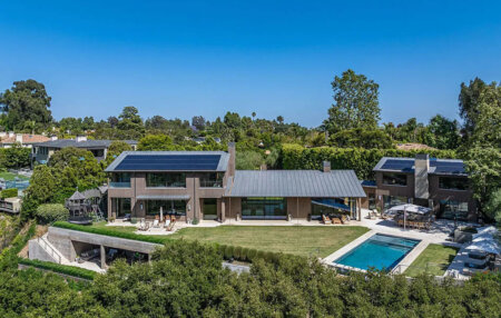 859 Woodacres Road main house | Santa Monica Sun Modern two-story home with solar panels, a spacious lawn, and a rectangular pool in the backyard.
