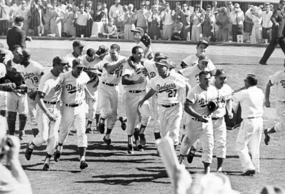 Los Ángeles Dodgers 1963 World Series | Santa Monica Sun Dodgers players celebrate on the field with fans applauding in the background, black-and-white photo.