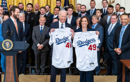 President and Vice President display Dodgers jerseys (numbers 46 and 49) at a White House event with a crowd behind them.