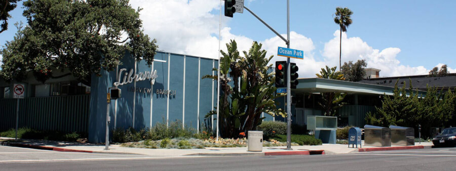 Blue library building at a street corner with a traffic light, Ocean Park sign, and palm trees on a sunny day