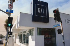GAP storefront on a sunny street corner with traffic lights, palm trees, and Wilshire Blvd signage in view.