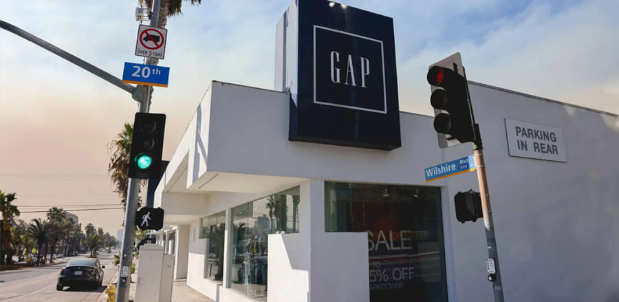 GAP storefront on a sunny street corner with traffic lights, palm trees, and Wilshire Blvd signage in view.