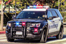 Police SUV with flashing red and blue lights driving on a street; Santa Monica Police markings on the side (POLICE).