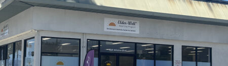 Exterior of Elder-Well Adult Day Program center with glass storefront and sign above entrance.