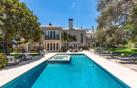 Luxurious backyard with a rectangular blue pool, lounge chairs, and a two-story villa with ivy-covered walls.