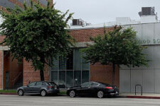 Brick school building with two trees in front, parked cars, and a metal-panel facade reading 'OLD SCHOOL'.