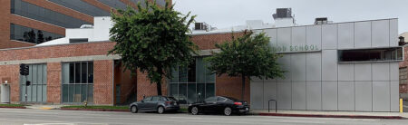 Brick school building with two trees in front, parked cars, and a metal-panel facade reading 'OLD SCHOOL'.