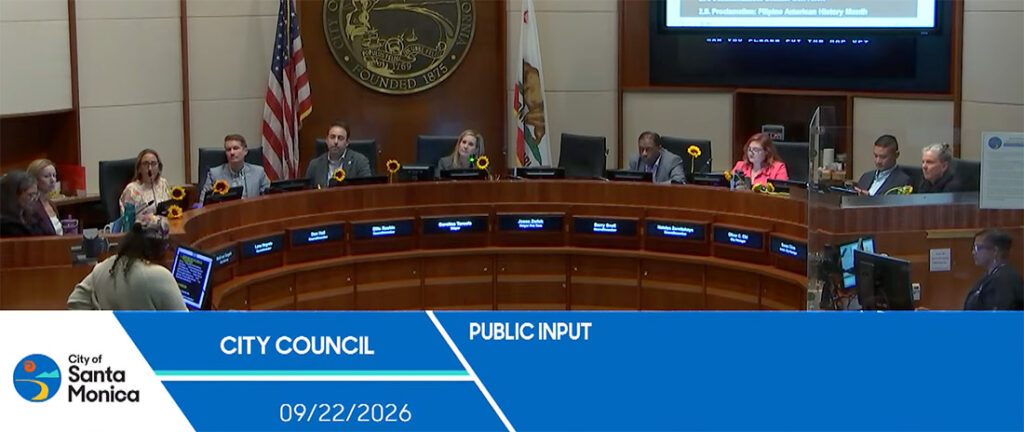 City Council chamber with members around a curved dais; flags and sunflowers on desks; blue 'Public Input' banner with date 09/22/2026 in front.