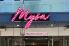 Storefront signage for Nysa with a pink neon logo above the entrance and a Mediterranean Grill sign below.